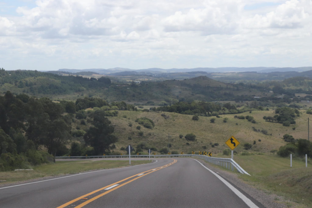 Blick auf eine unbefahrene kurvige Straße mit Panoramablick auf eine hügelige grüne Landschaft